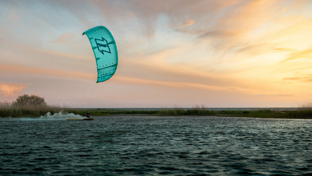 Person kitesurfer på blåt vand mod lilla himmel