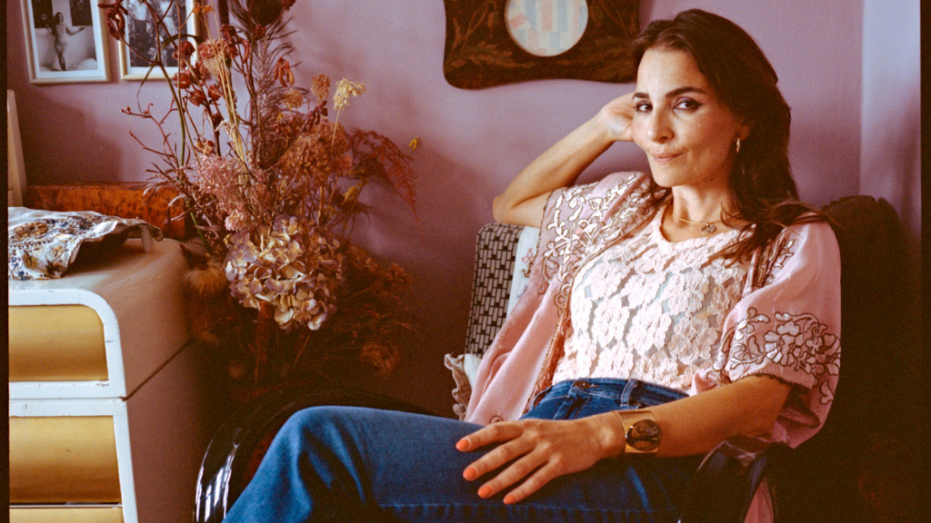 Evren Tekinoktay sits in an armchair in a pink room, looking into the camera
