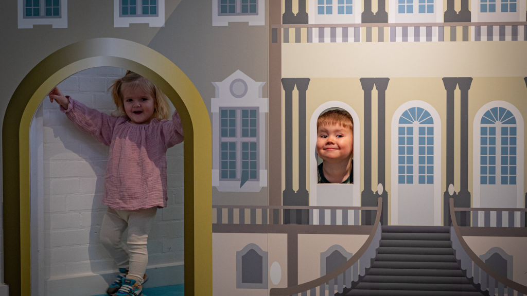 To børn leger i et stort dukkehus
