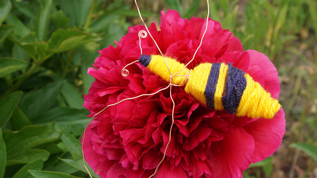 En bi i garn sidder på en blomst