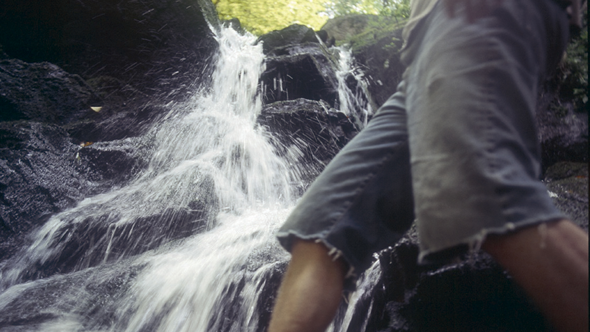 Eine Person planscht im Døndalen-Wasserfall