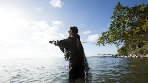 mand fisker i waders ved kysten
