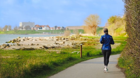 Løber løber tur langs Østerstrand og Hyby strand på ruten Strandstien. Det er forår. hun løber med ryggen til kameraet.