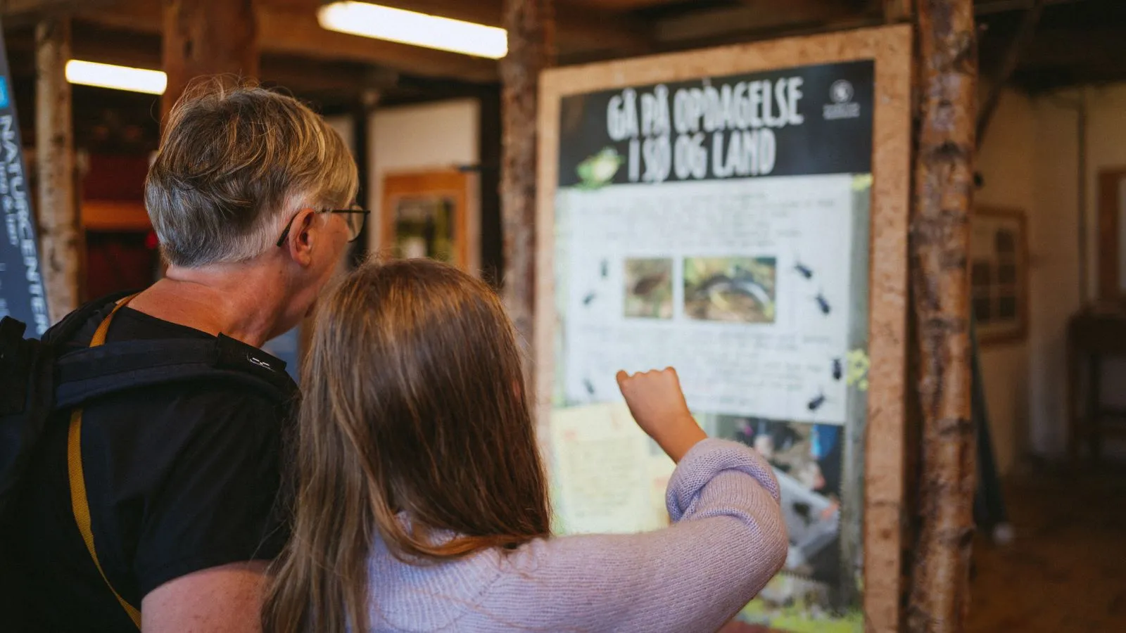 A family reads information posters in the Nature Center Trelde Næs.