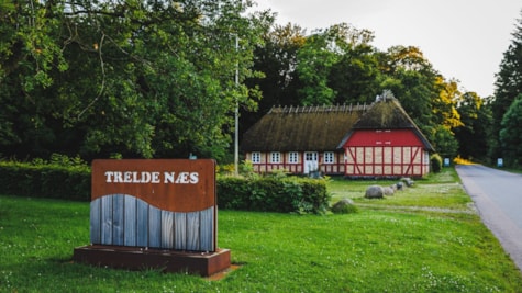 Indkørsel til Trelde Næs. I baggrunden ses en gammel gård.