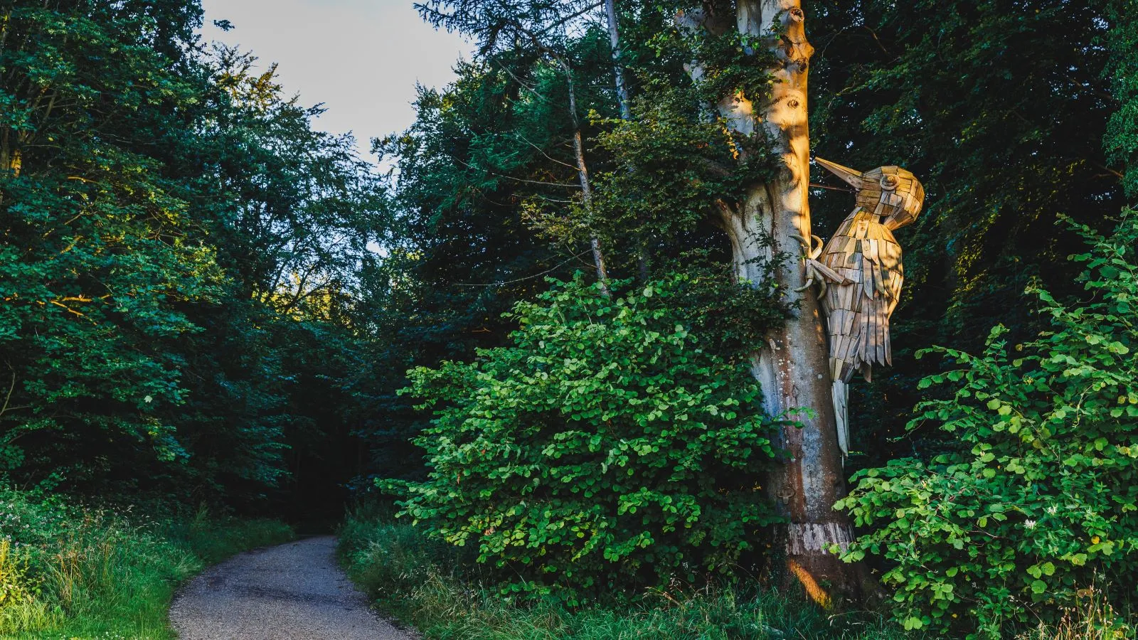 Wooden sculpture shaped like a woodpecker hanging in the treetops at Trelde Næs.