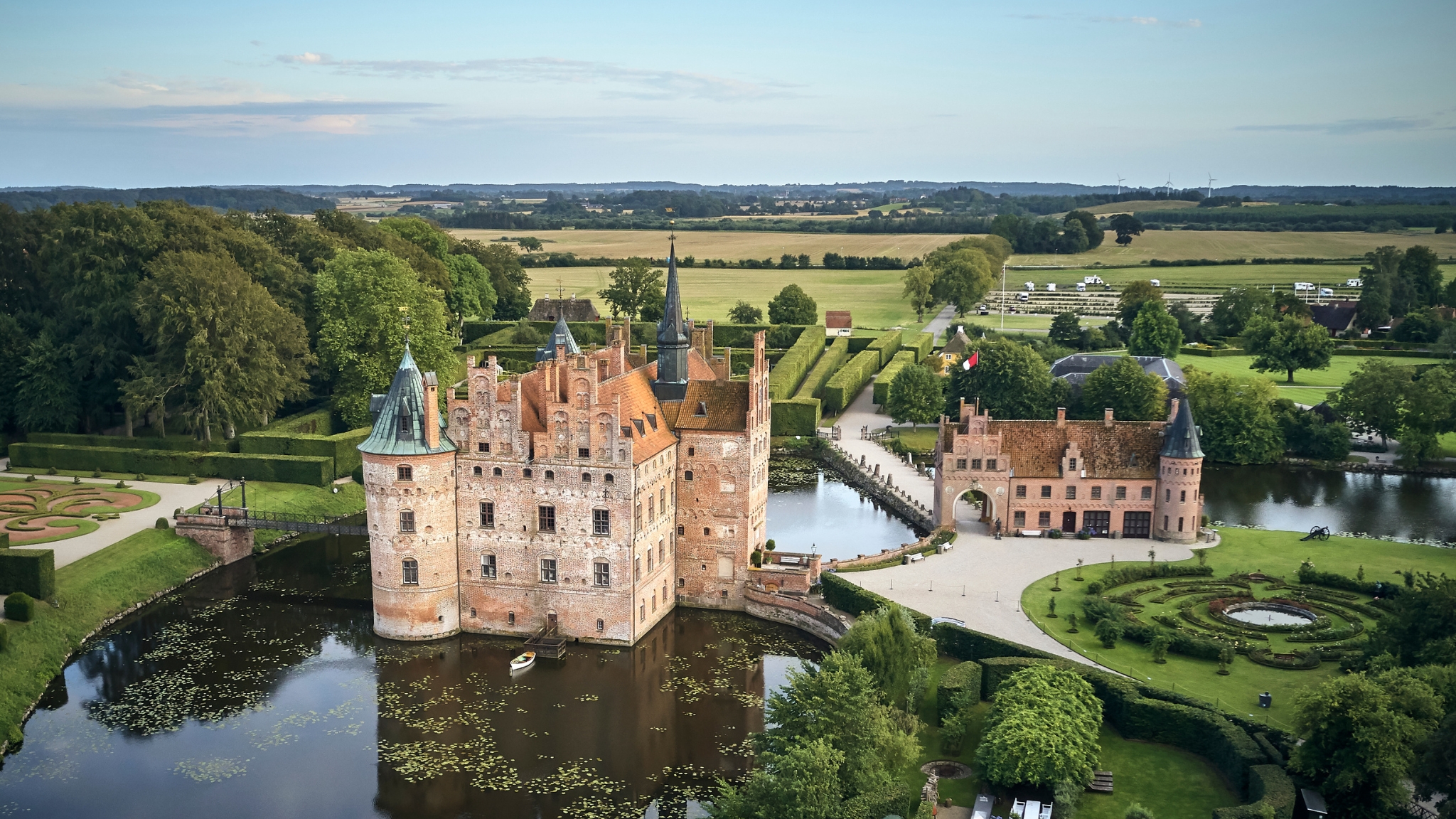 Egeskov Castle seen from above, with its moat, symmetrical gardens and the South Funen countryside in the background.
