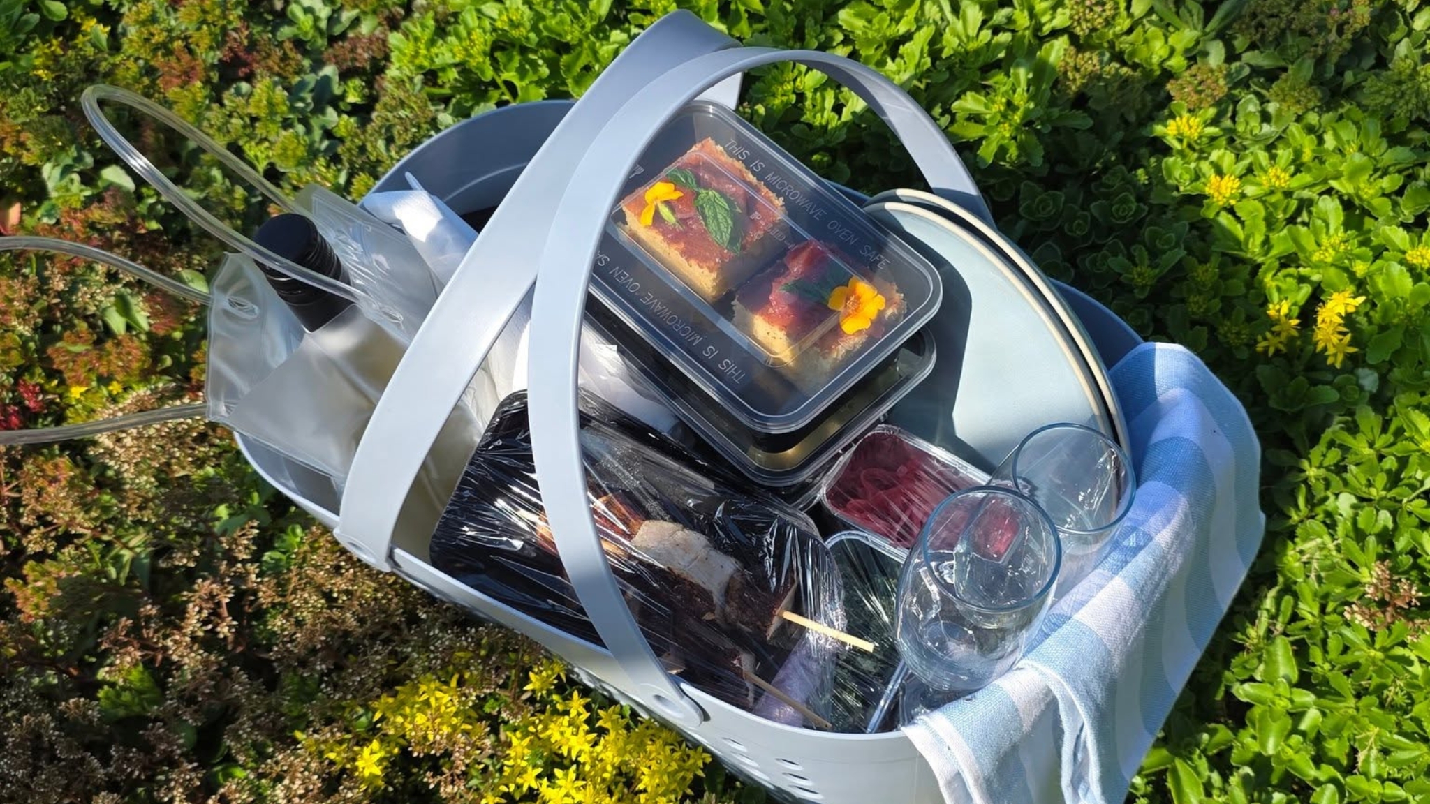Picnic basket from Café Himmelblå with wine, charcuterie, cheeses, cake and glasses, ready for an outdoor picnic in Faaborg.