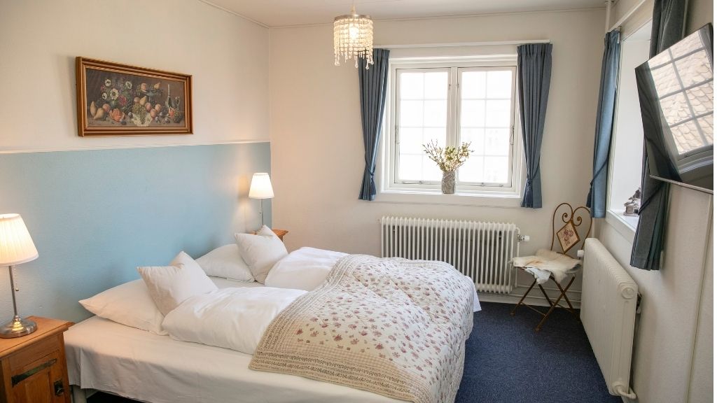 Dobbeltværelse på Hotel Faaborg med lyse farver, tv og komfortable senge.