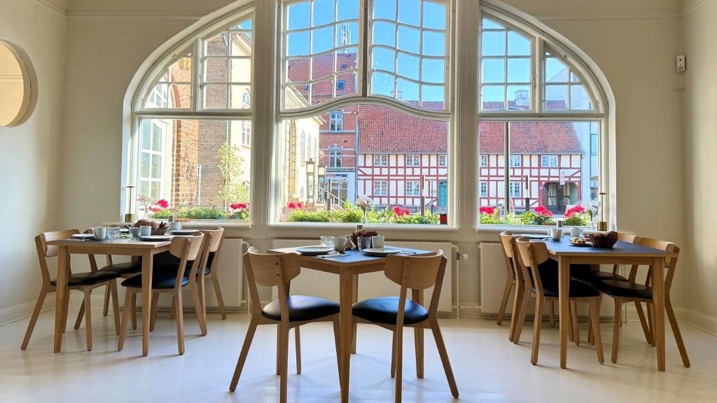 Lys restaurant på Hotel Faaborg med dækkede borde og udsigt til den historiske bymidte.
