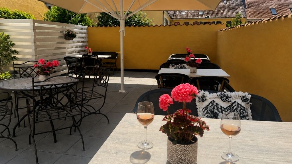 Hyggelig gårdhave på Hotel Faaborg med borde, parasol og afslappet atmosfære.