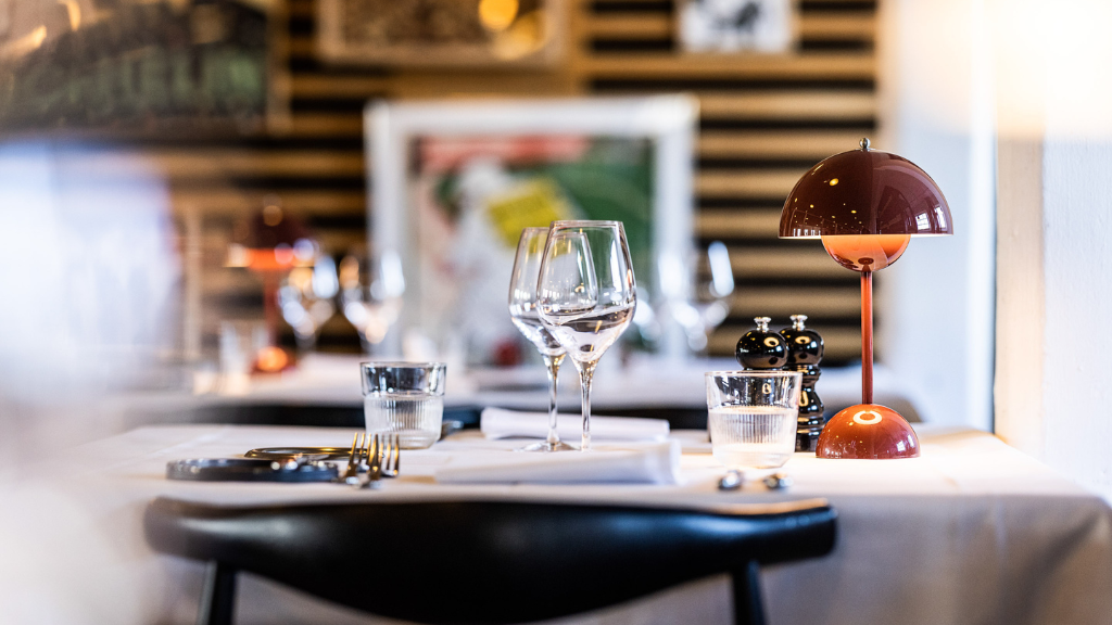lampe lyser på bord med glas og service
