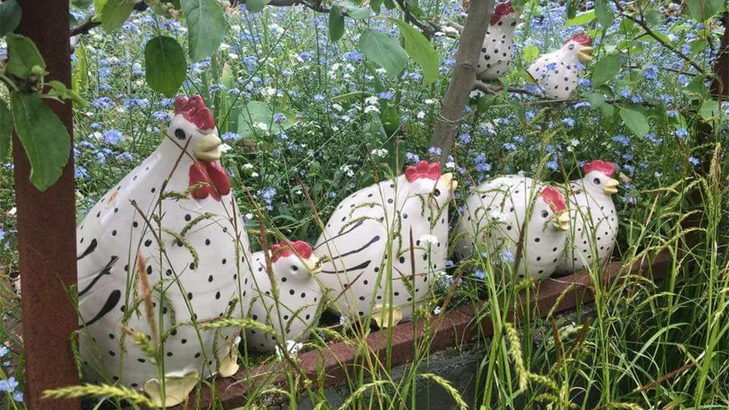Høns lavet i keramik står i græs