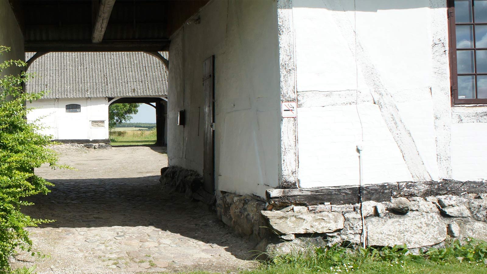 Historisk Kongsgaarden i Vester Broby, en firlænget gård med røde bygninger omgivet af grønne marker og landlig idyl.