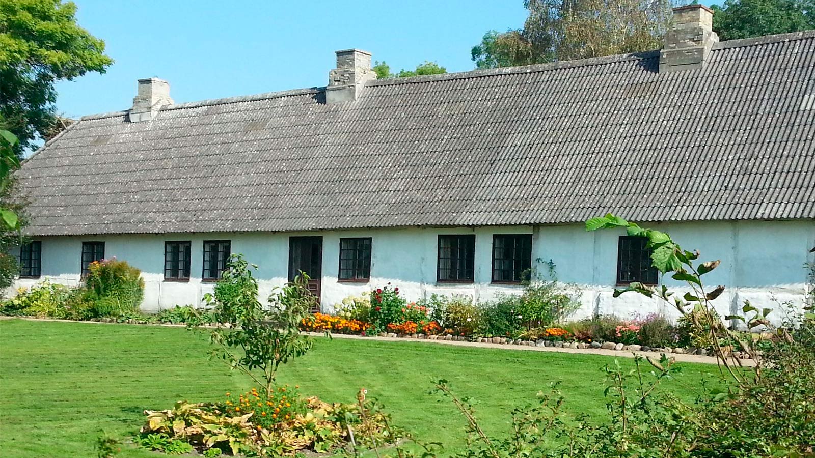 Historisk Kongsgaarden i Vester Broby, en firlænget gård med røde bygninger omgivet af grønne marker og landlig idyl.