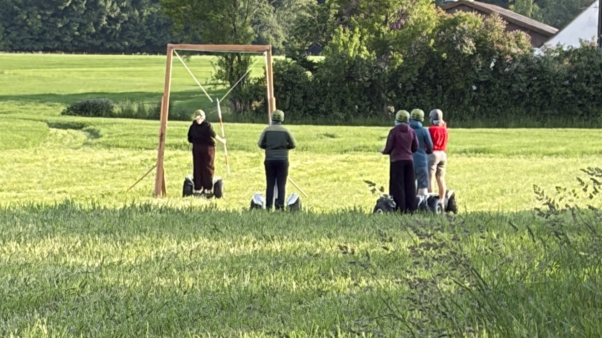 Instruktør i grøn trøje introducerer fem deltagere med hjelm på Segway-terrængående i et grønt naturområde.