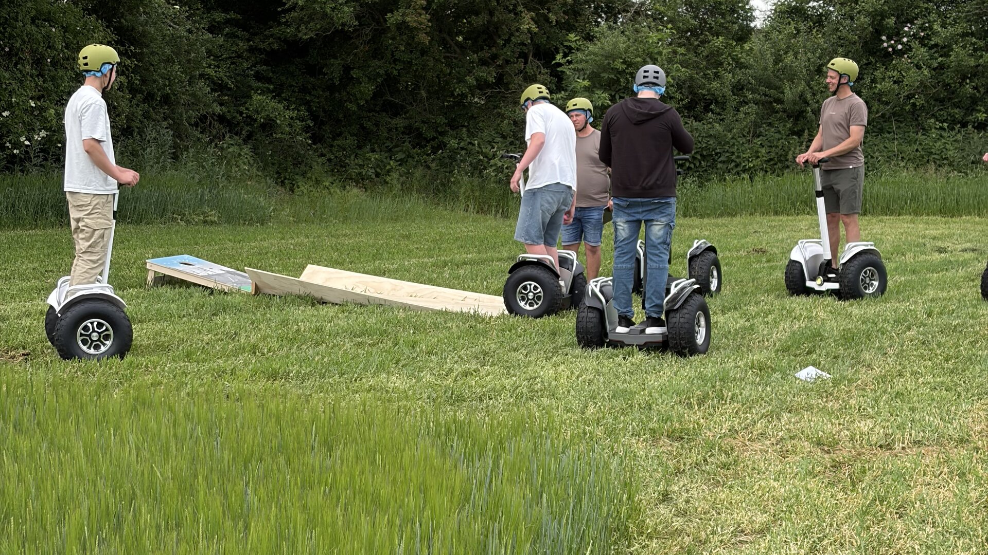 Instruktør i grøn trøje introducerer fem deltagere med hjelm på Segway-terrængående i et grønt naturområde.