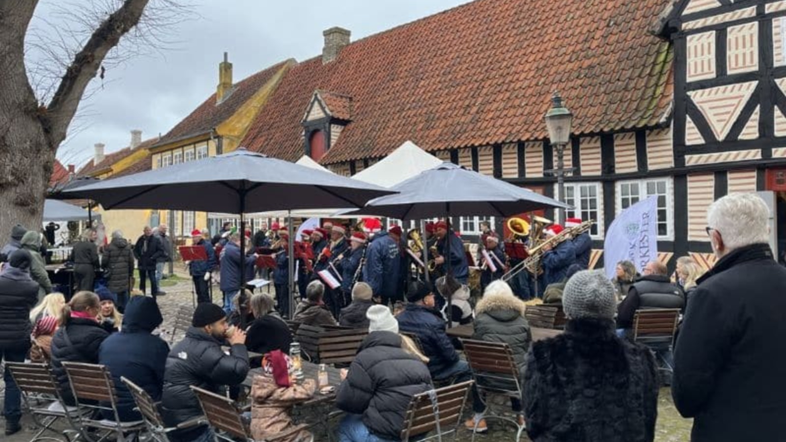 Band in Santa hats playing among half-timbered houses at the Christmas market at Holbæk Museum