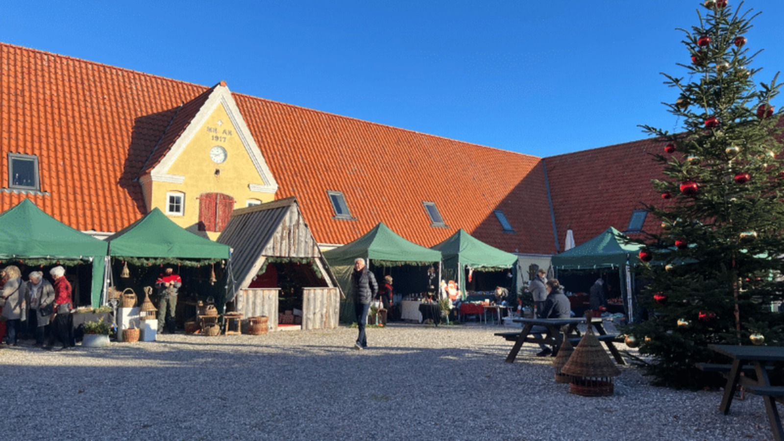 Green market stalls and a decorated Christmas tree in the courtyard at the Christmas market at Dyrehøj Vineyard on Røsnæs