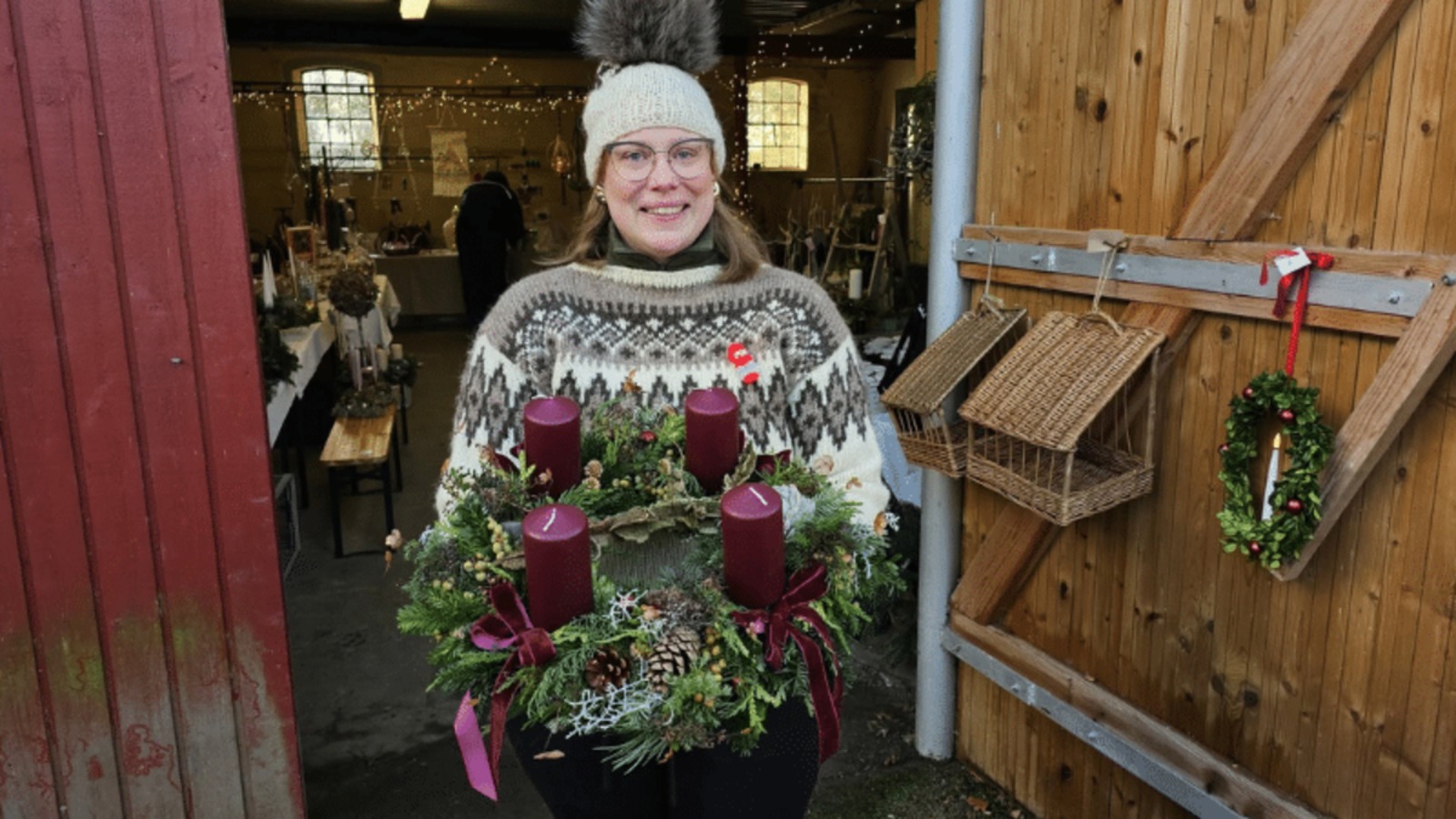 Woman holding a handmade Advent wreath in the barn at the Christmas market at Bakkegaarden near Store Merløse