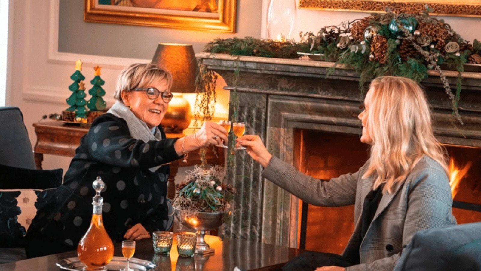 Zwei Gäste stoßen vor dem Kamin in den weihnachtlich geschmückten Räumen von Gut Kragerup an