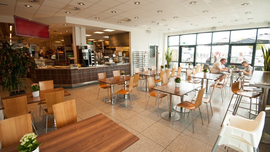 The small cafe at SuperBrugsen seen from the inside. The cafe has many chairs and tables.