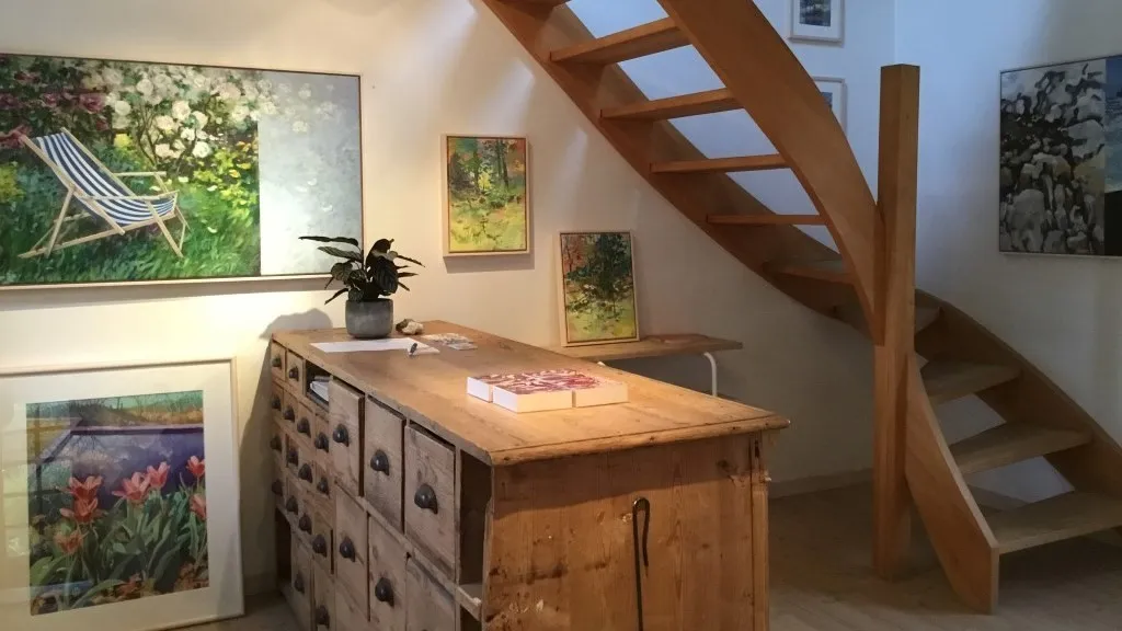 Photograph of Galleri Brogaard from the inside, showing some of Brogaard's paintings hanging under a staircase.