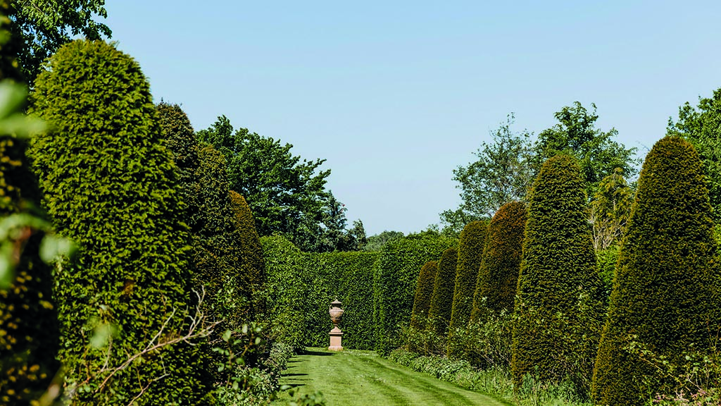 Humlemagasinets have med skulptur forenden. På en sommerdag med grønne træer