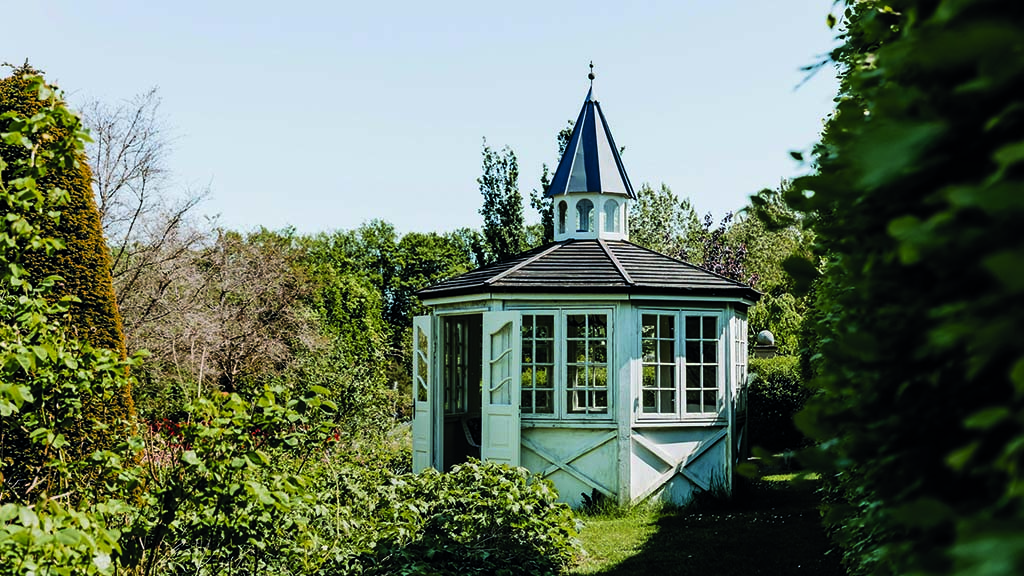 Lysthus/orangeri omgivet af træer i Humlemagasinets have