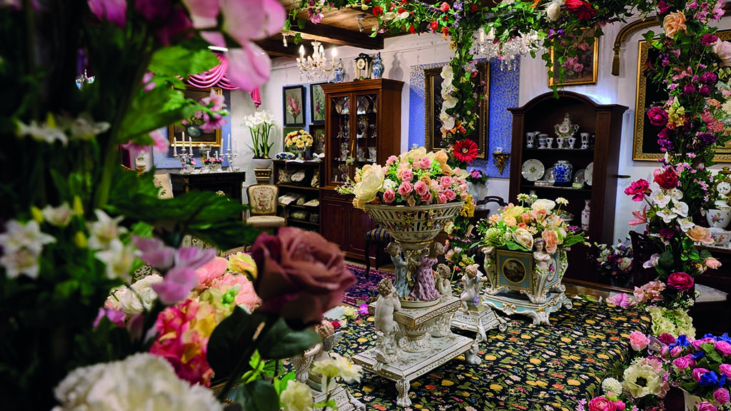 På billedet ses et rum i Humlemagasinet. Rummet er fyldt med blomster og Victorianske møbler og porcelæn