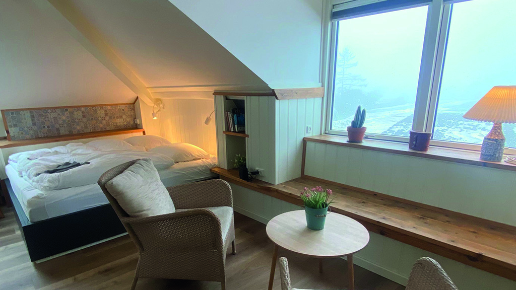 Zimmer in einer Wohngemeinschaft. Das Zimmer ist gemütlich eingerichtet und bietet ein Doppelbett, zwei Stühle und einen kleinen Tisch. Es hat eine schöne Aussicht.