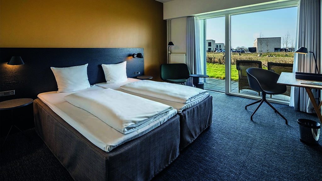 Room with a large window. The room has a modern interior and a small desk.