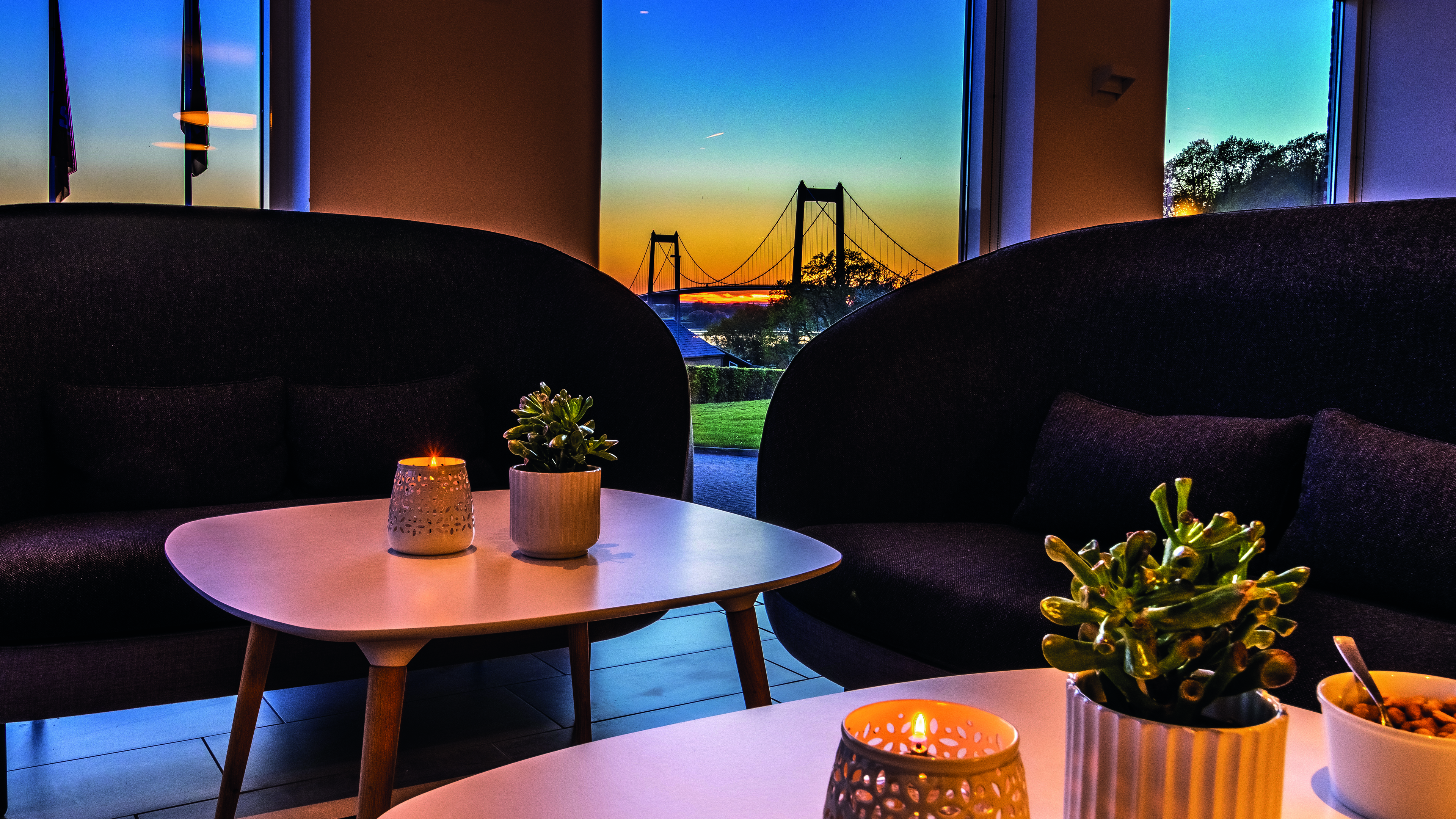 Loungebereich im Hotel Severin. Im Hintergrund die Neue Kleine Beltbrücke im Sonnenuntergang.