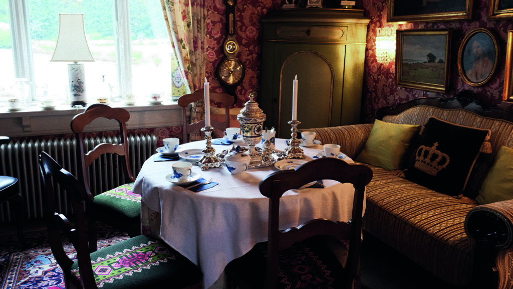 Café in the Humlemagasinet. Tables are set with vintage china, and the space is furnished with antique objects and furniture.