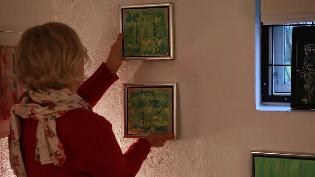 Artist Sonja Foged hangs small paintings on the wall