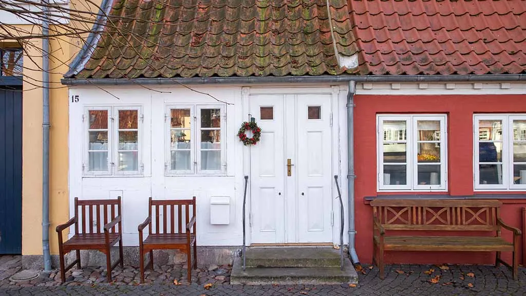 Bogense's smallest house with white paint and wooden chairs in front