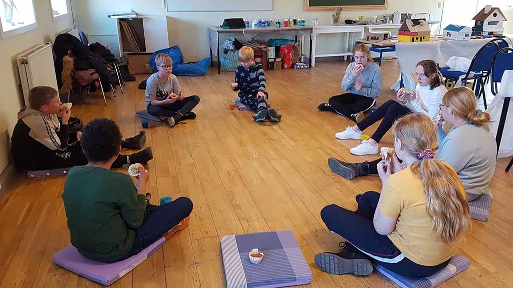 A group of children sits in a circle and eats cake