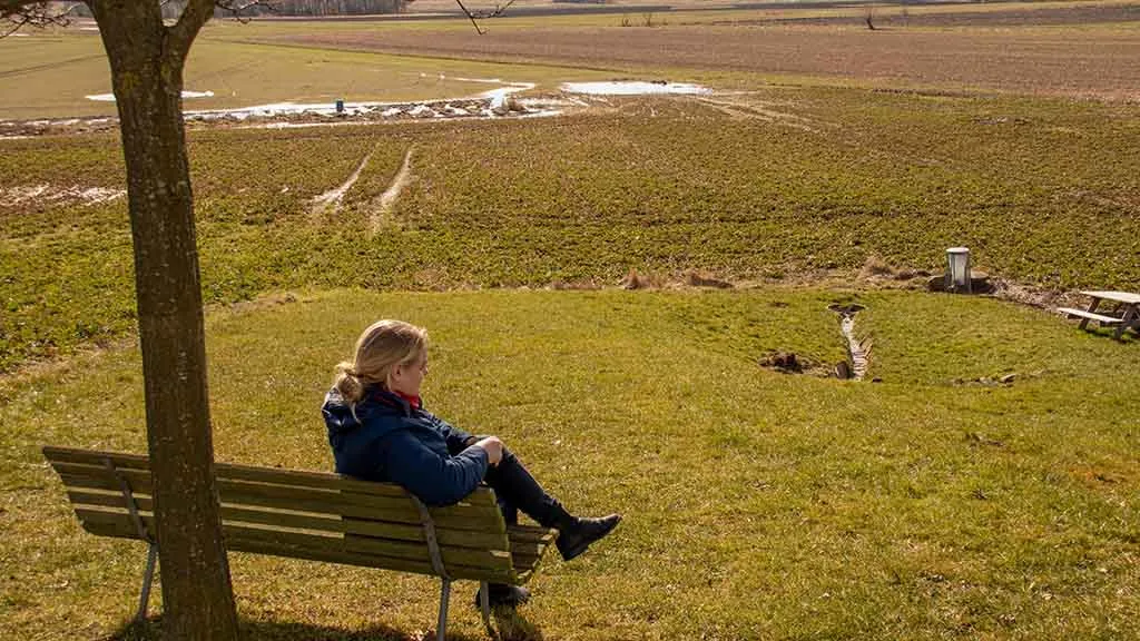 Woman relaxes on the bench on the hill above Sankt Oluf's spring