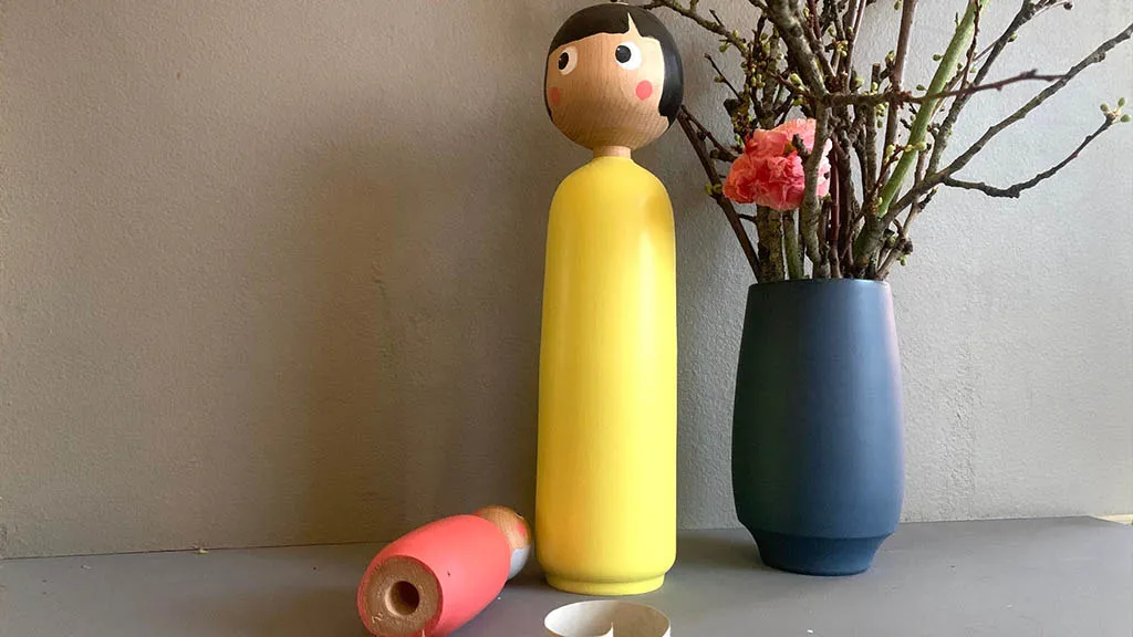 Yellow Miss U figure and blue wooden vase