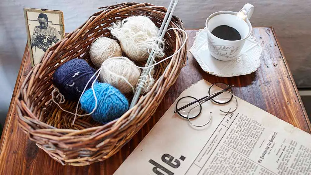 Yarn in a basket, coffee cup and newspaper and glasses on the table at Otterup Museum