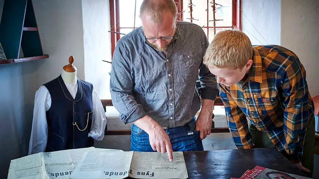 Gæster kigger i en gammel avis på Otterup Museum