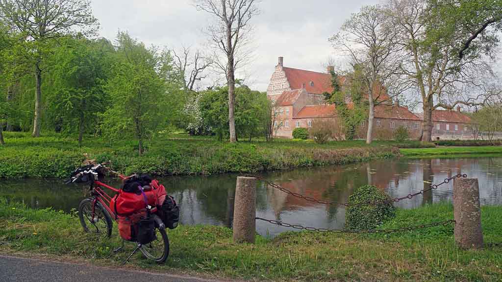 A bicycle stands by the moat in front of Gyldensteen castle on the castle route