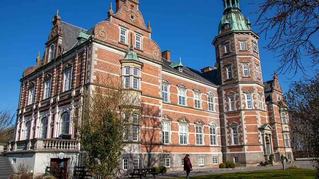 Østruplund seen from the side, while a woman walks in front