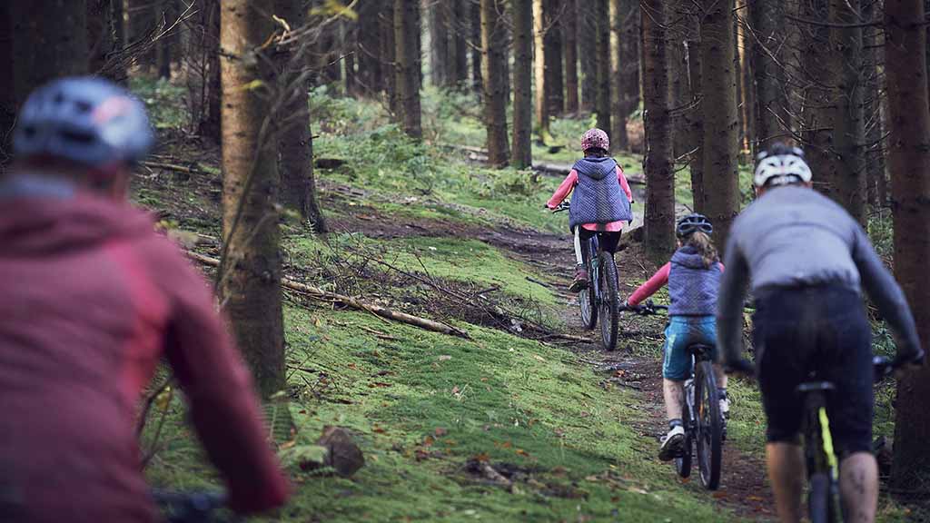 Family cycling at full speed on the MTB track in Langesø Forest