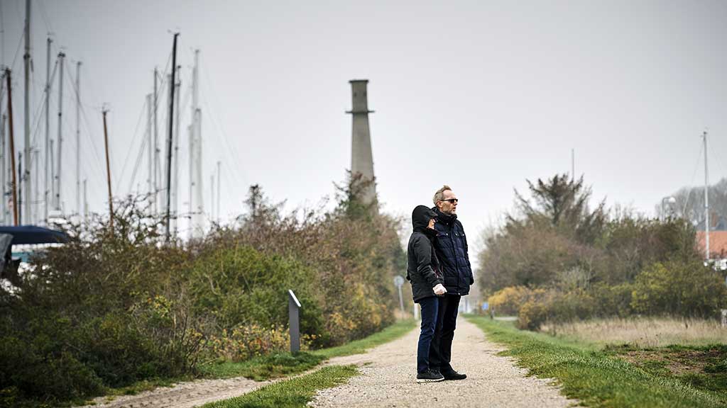 An elderly couple looks out from the clover path next to Bogense Marina in winter