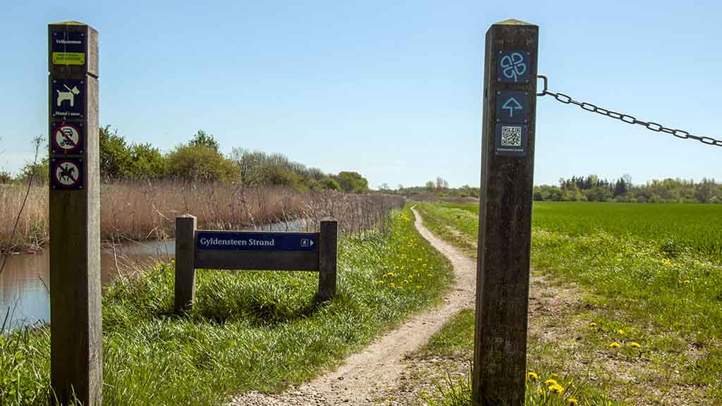 The sign for the green clover leaf route at Gyldensteen Strand next to the canal in summertime