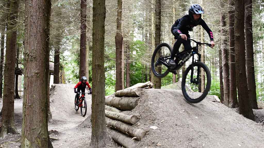 Two young cyclists ride on the MTB track on hills in the Langesø forest