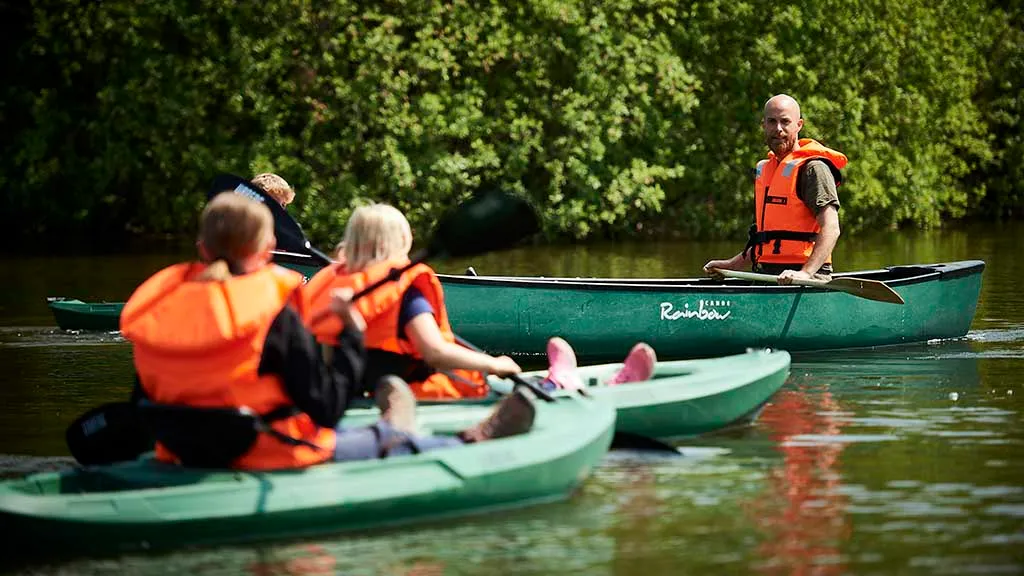 Children and an adult sail in canoes in Funen's Sommerland