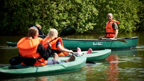 Børn og en voksen sejler i kanoer i Fyns Sommerland