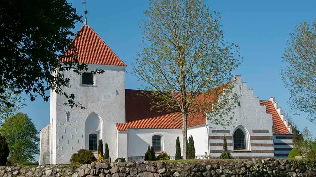 Søndersø Church and the church tower with tall trees in front
